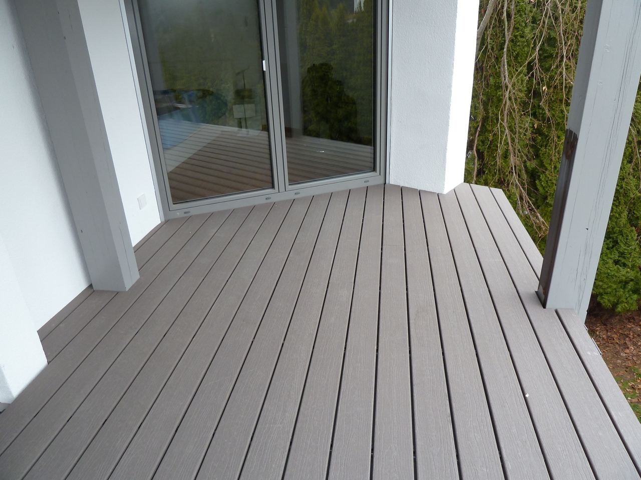 Balkon mit grauen WPC-Dielen und weißen Putzstützen