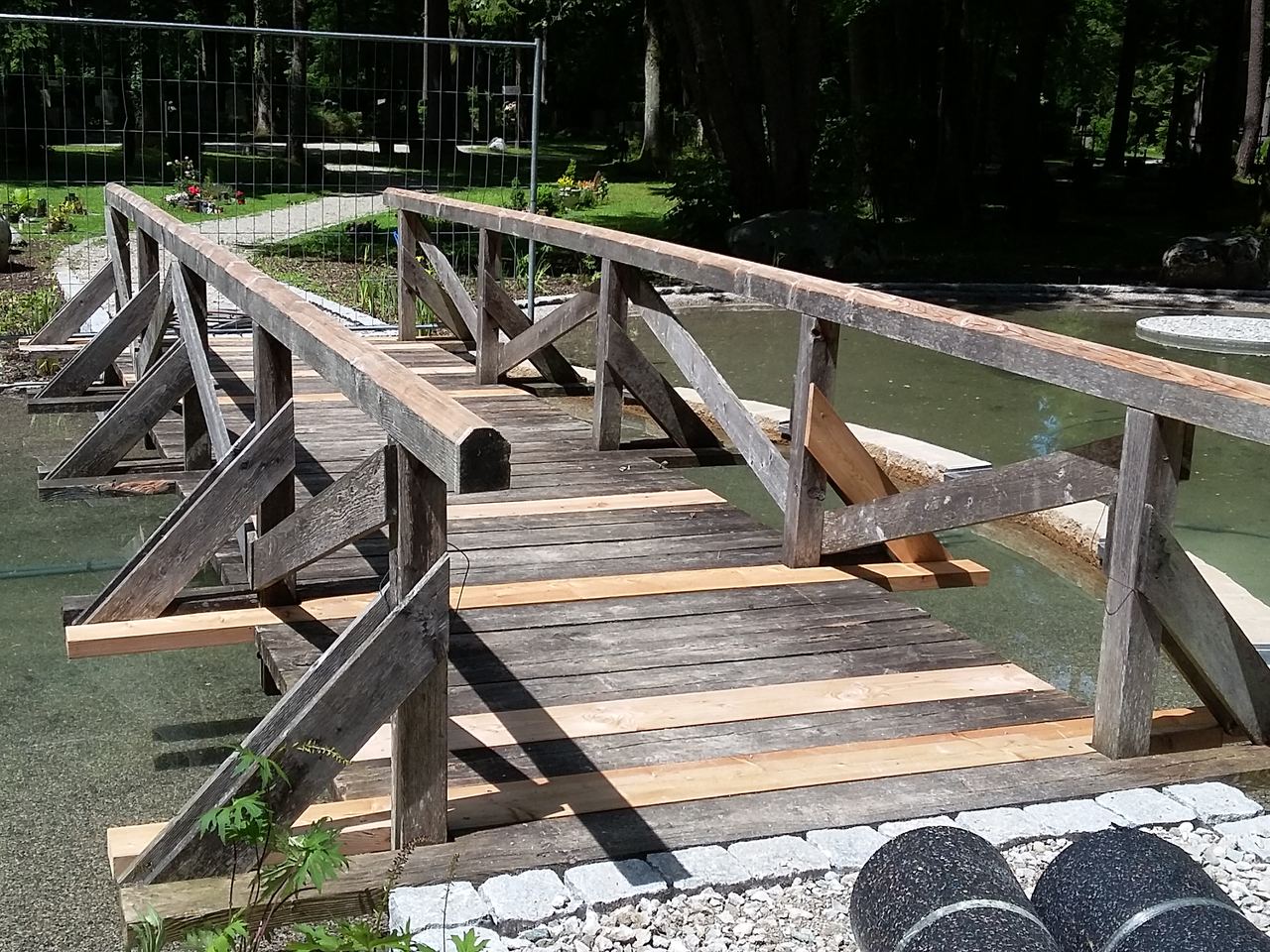 Hölzerner Steg mit Geländer über einen Teich