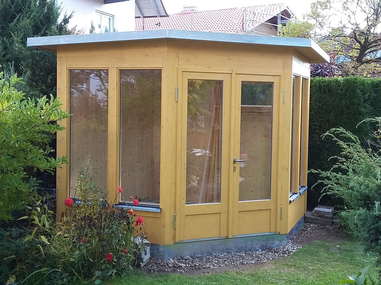 Gartenpavillon aus Holz mit großen Glasflächen und Flachdach