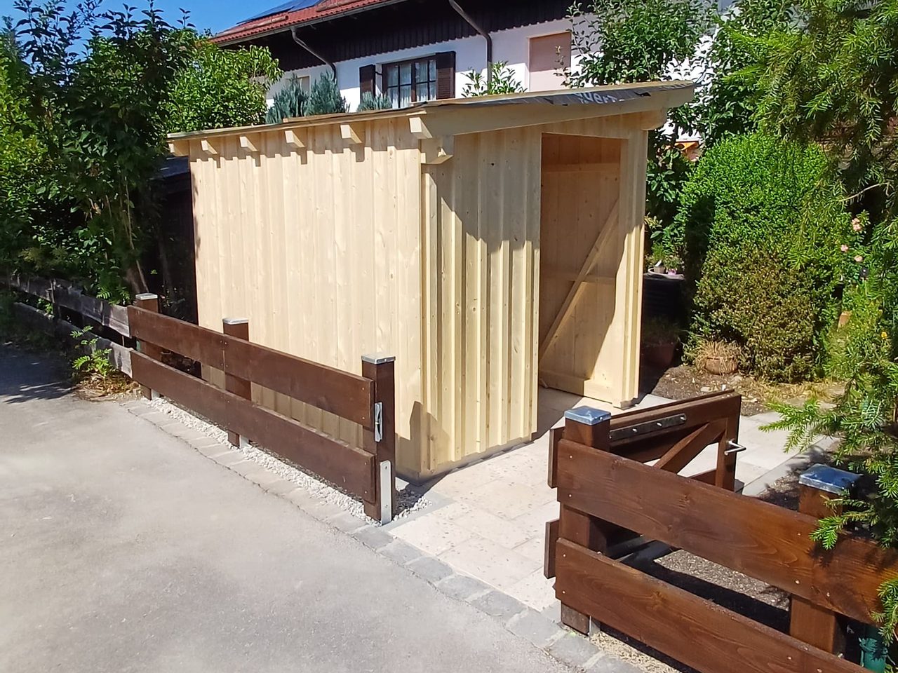 Neu gebauter Geräteschuppen aus hellem Fichtenholz mit Pultdach an einer Grundstückszufahrt