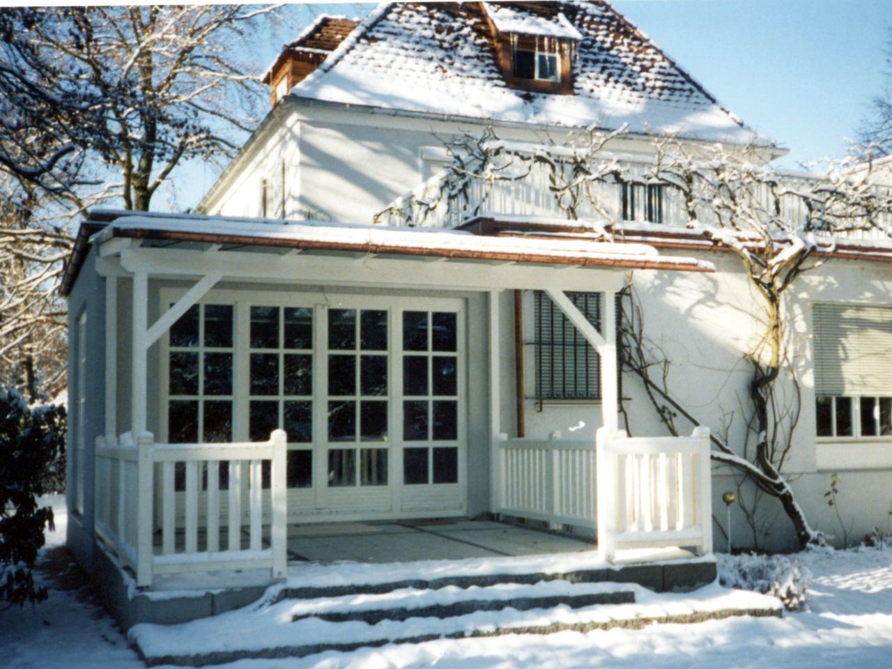 Verglaste Veranda mit weißer Holzbalustrade an einer Villa im Winter